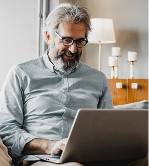 Photo of a mature man at home. He is using a laptop.