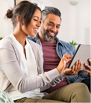 Photo d’un heureux couple multiethnique d'âge mûr utilisant une tablette numérique pour un paiement en ligne par carte de crédit.