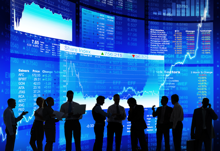 Decorative image: a group of people in front of various stock market indexes in blue. 